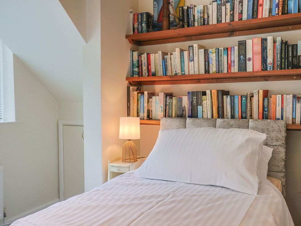 A bedroom with a bed and bookshelf at Hawksdown in Lyme Regis