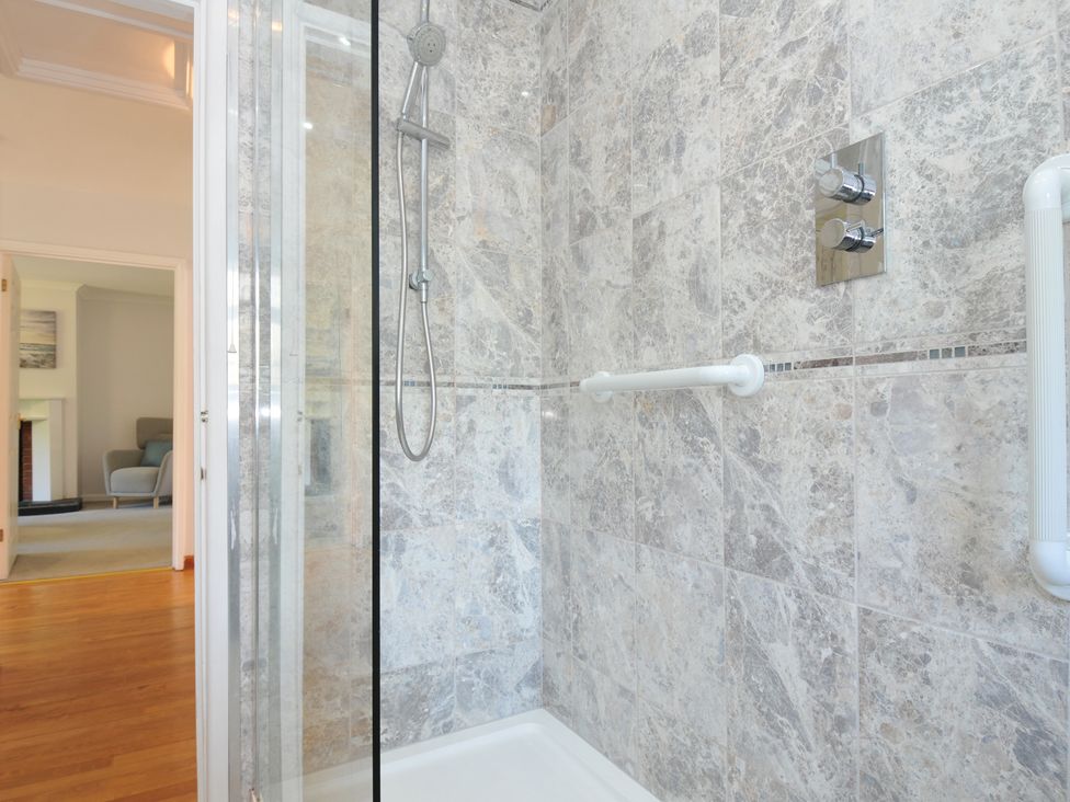 A shower with a glass door and tiled walls at Jazmine in Dacre