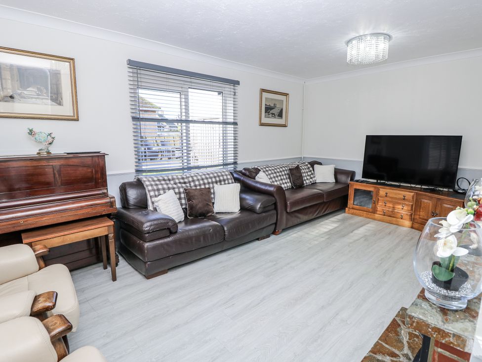A living room with a piano and television at Red Brick Haven in East Cowes, Isle Of Wight