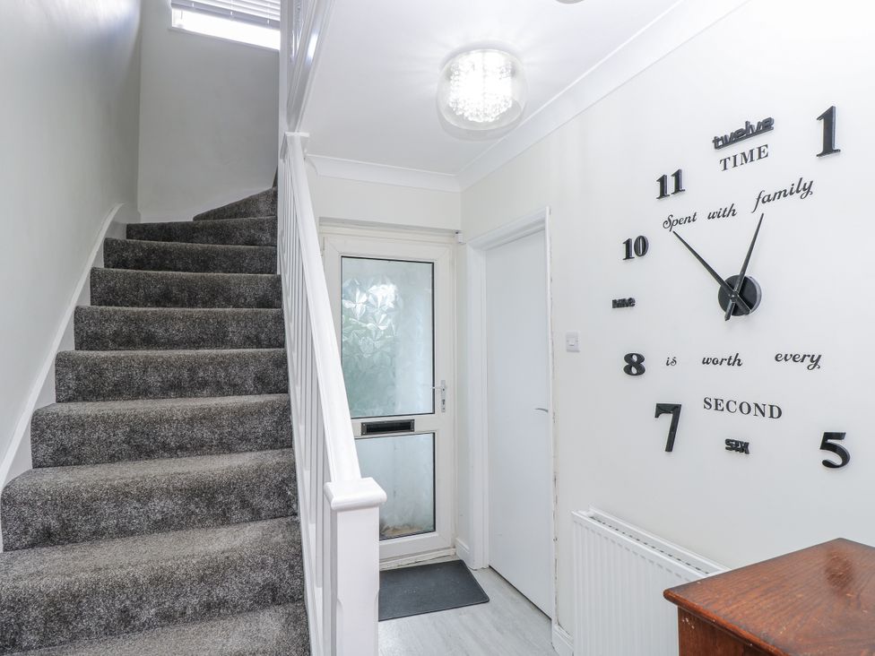 A hallway with a staircase and wall clock at Red Brick Haven East Cowes, Isle Of Wight