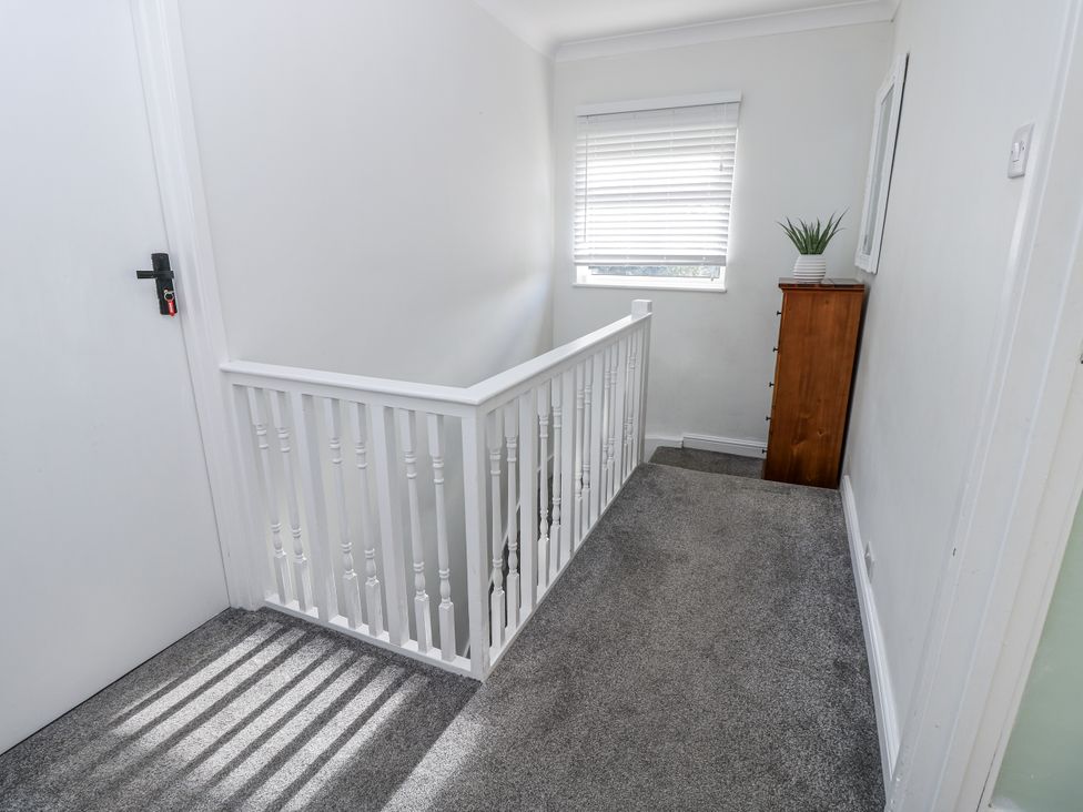 A hallway with a railing and a dresser at Red Brick Haven in East Cowes, Isle Of Wight