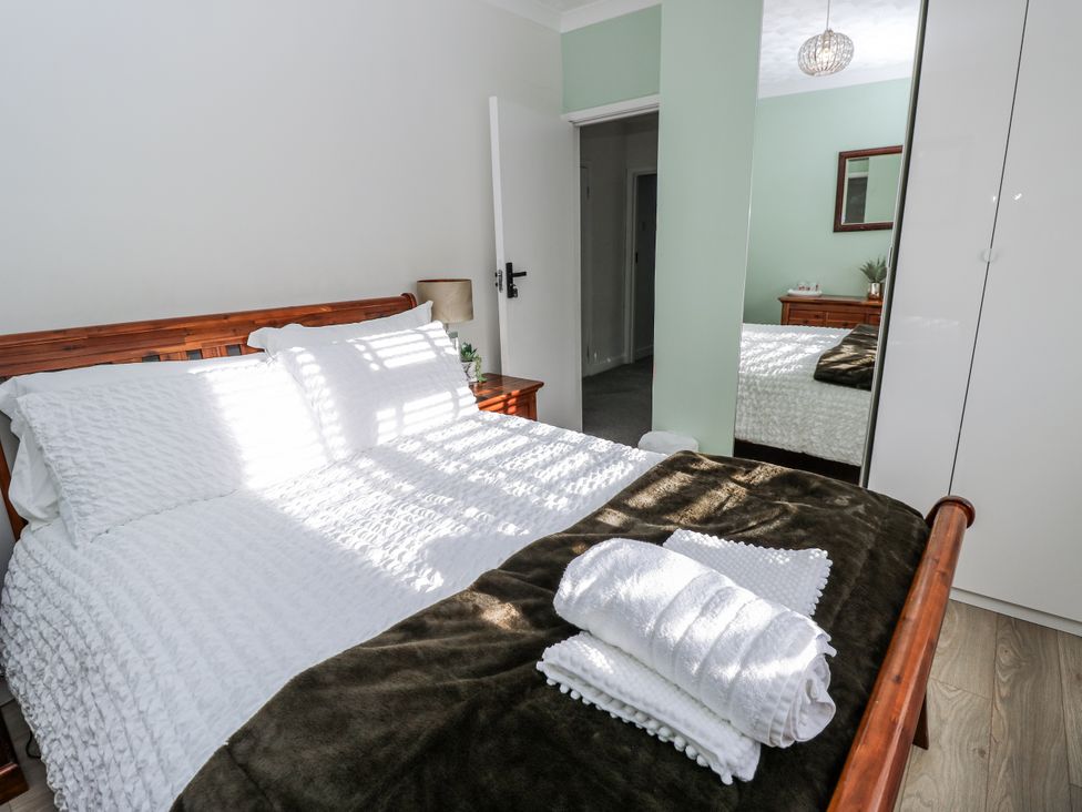A bedroom with a bed, bedside table, and mirror at Red Brick Haven in East Cowes, Isle Of Wight