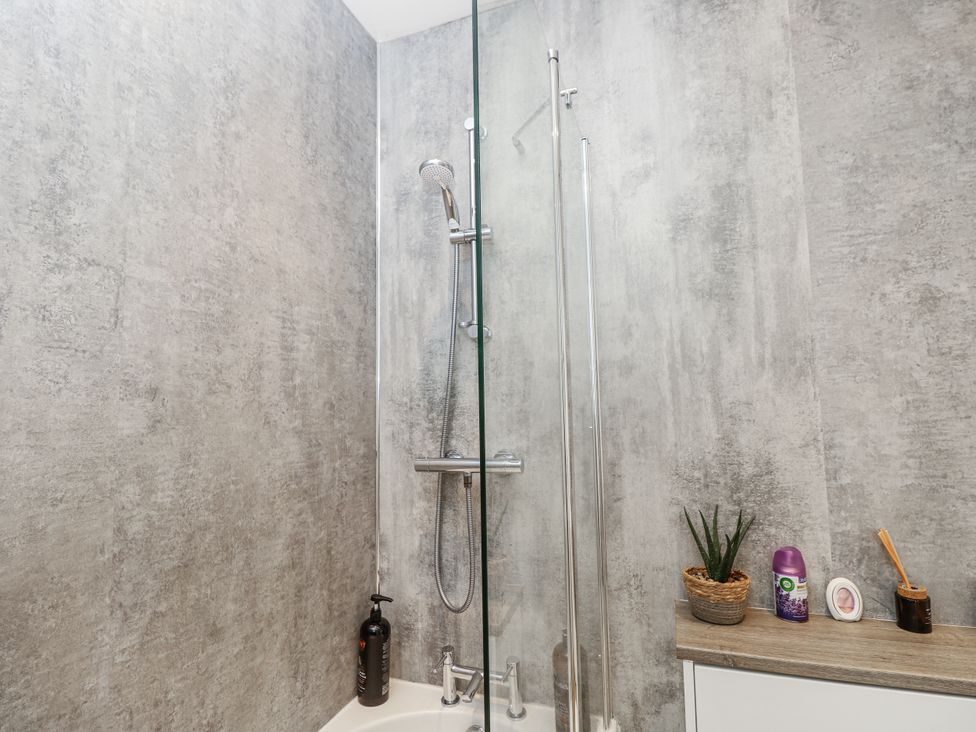 A shower with a glass panel and a shelf at Red Brick Haven in East Cowes, Isle Of Wight