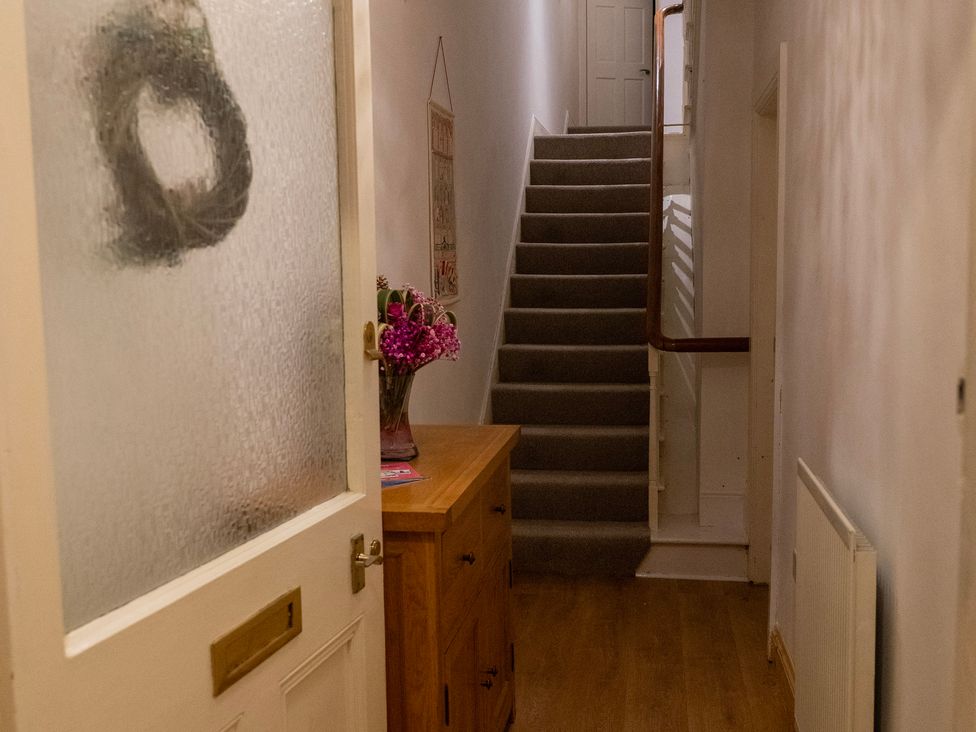 A hallway with a stairs and a table with flowers at The Red Door 