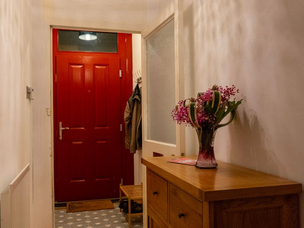 A hallway with a red door and flowers on a table at The Red Door 