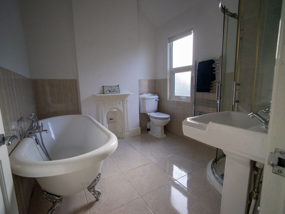 A bathroom with a bathtub, toilet, sink, and shower at The Red Door in Bangor