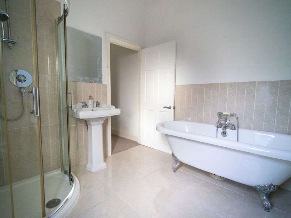 A bathroom with a shower, bathtub, and sink at The Red Door in Bangor