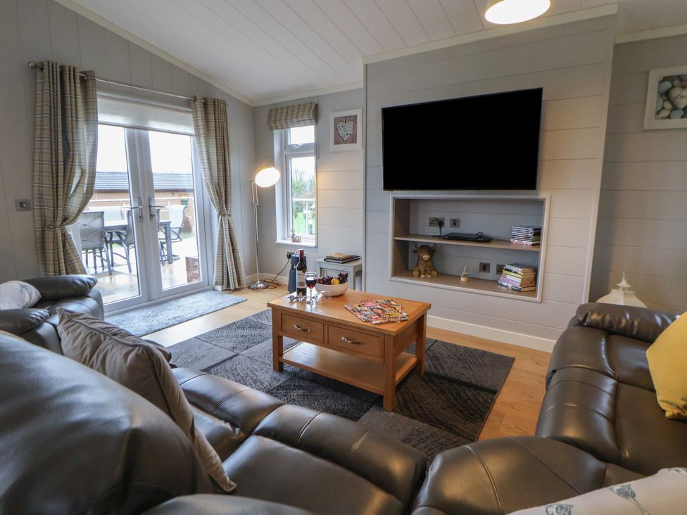 A living room with a sofa and coffee table at Holly Lodge in Lloc near Caerwys