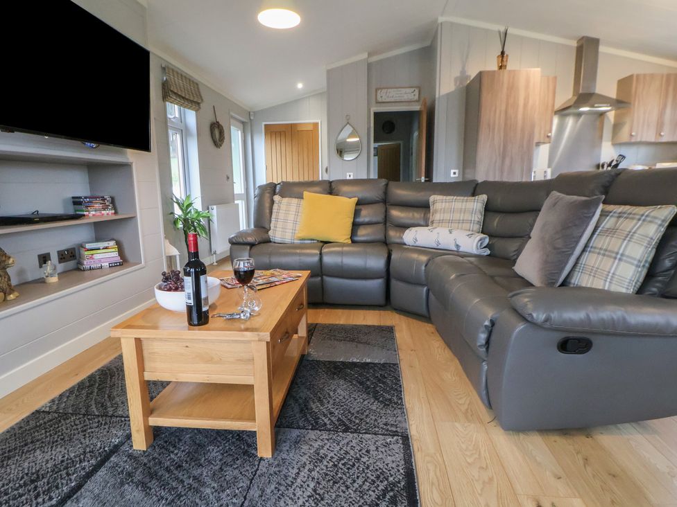 A living room with a grey sofa and coffee table at Holly Lodge in Lloc near Caerwys