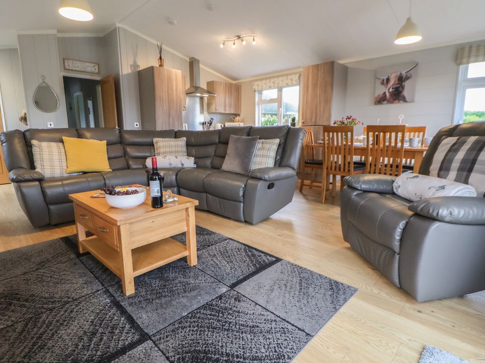 A living room with a sofa and coffee table at Holly Lodge in Lloc near Caerwys