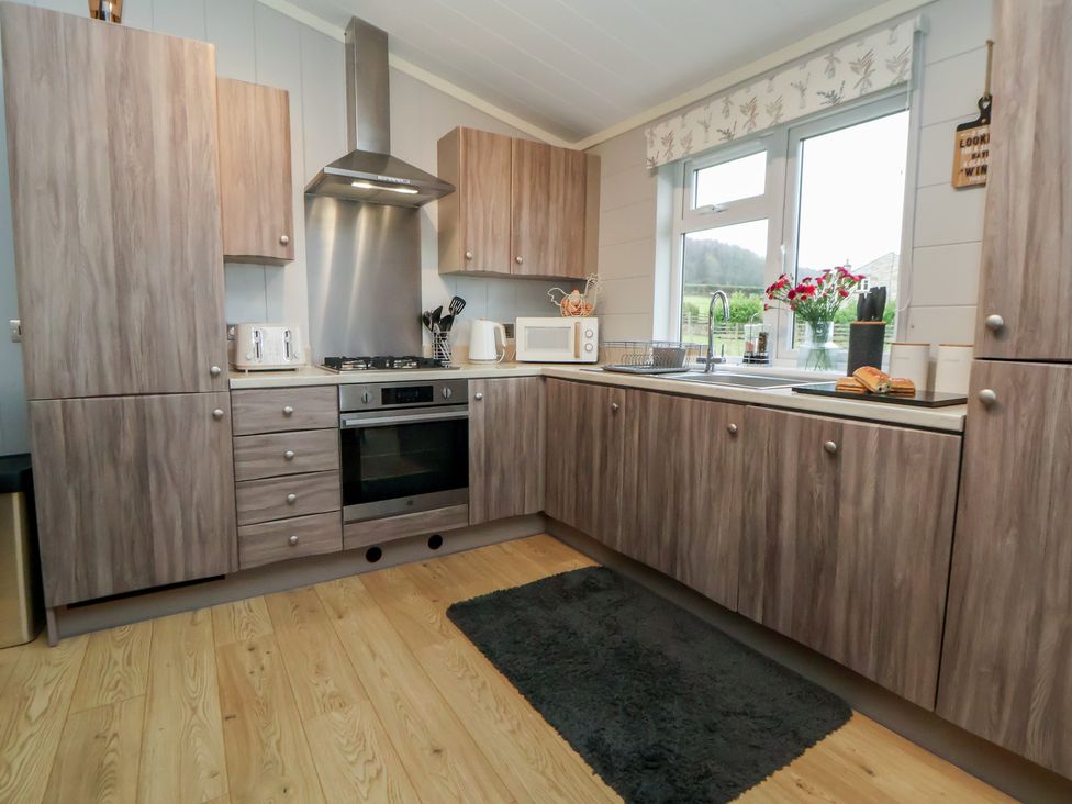 A kitchen with cabinets and appliances at Holly Lodge in Lloc near Caerwys