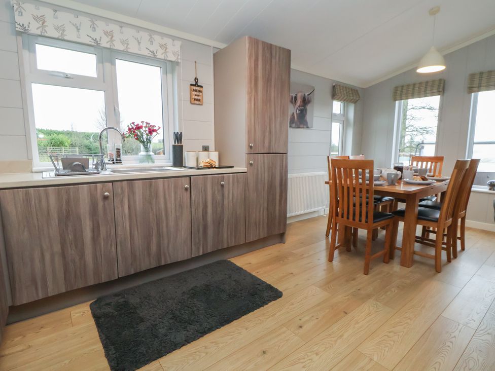 A kitchen with sink and dining area at Holly Lodge in Lloc near Caerwys