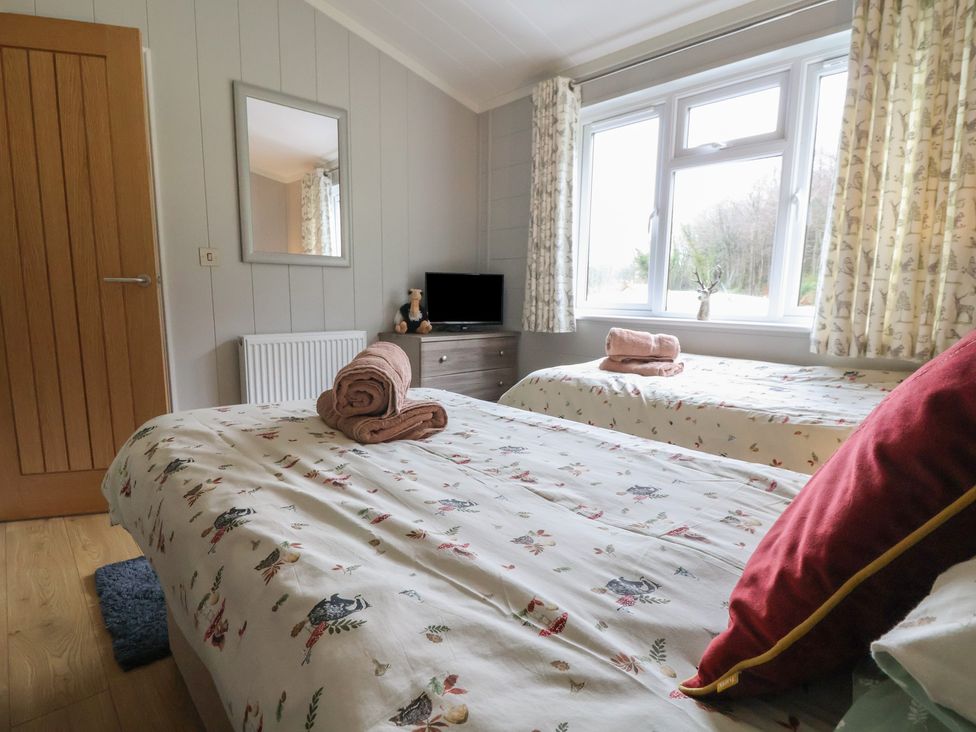 A bedroom with twin beds and a tv at Holly Lodge in Lloc near Caerwys