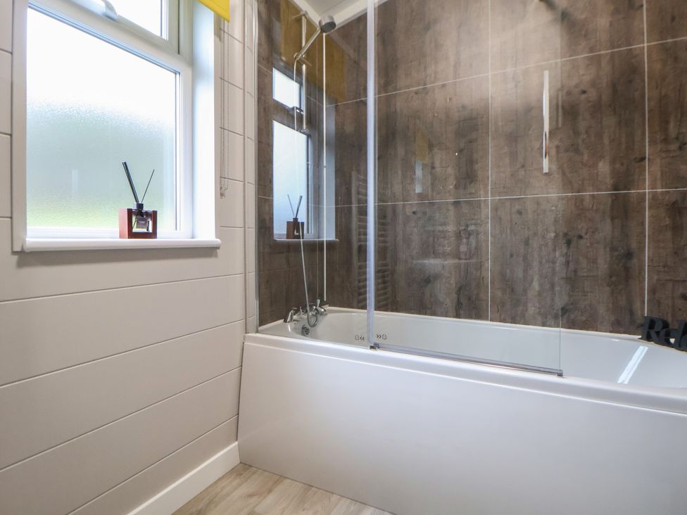 A bathroom with a bathtub and shower at Holly Lodge in Lloc near Caerwys