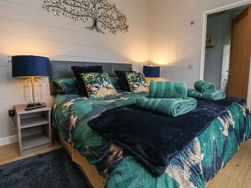 A bedroom with a bed and bedside table at Holly Lodge in Lloc near Caerwys