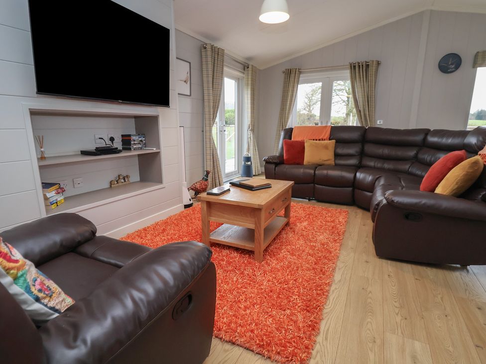 A living room with a sofa and television at Pine Lodge Lloc near Caerwys