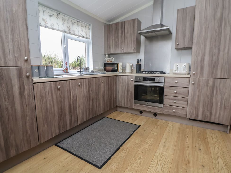 A kitchen with wooden units and stainless steel appliances at Pine Lodge in Lloc near Caerwys
