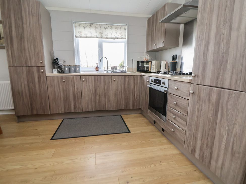 A kitchen with a sink, microwave, and oven at Pine Lodge in Lloc near Caerwys