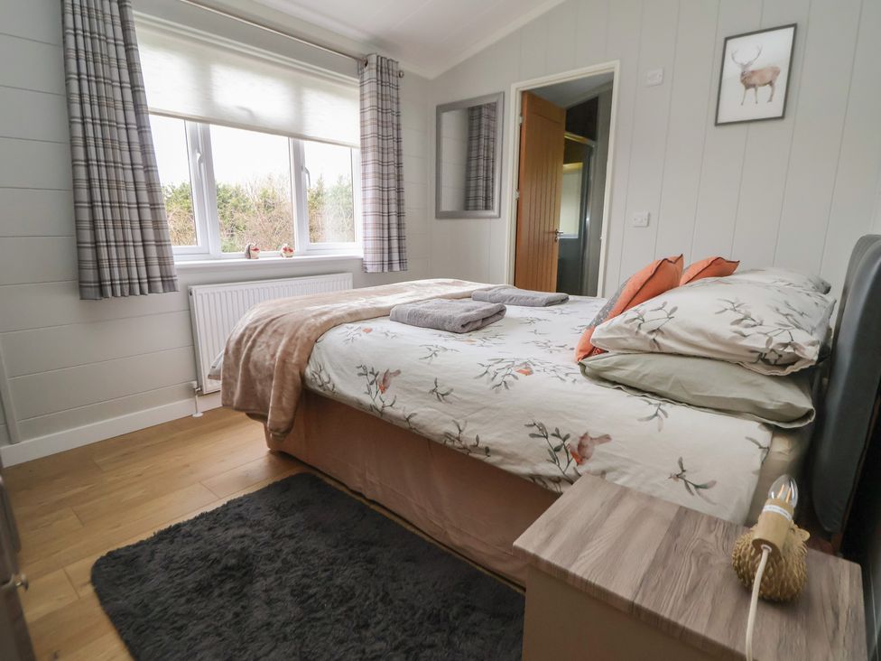 A bedroom with a bed and curtains at Pine Lodge in Lloc near Caerwys