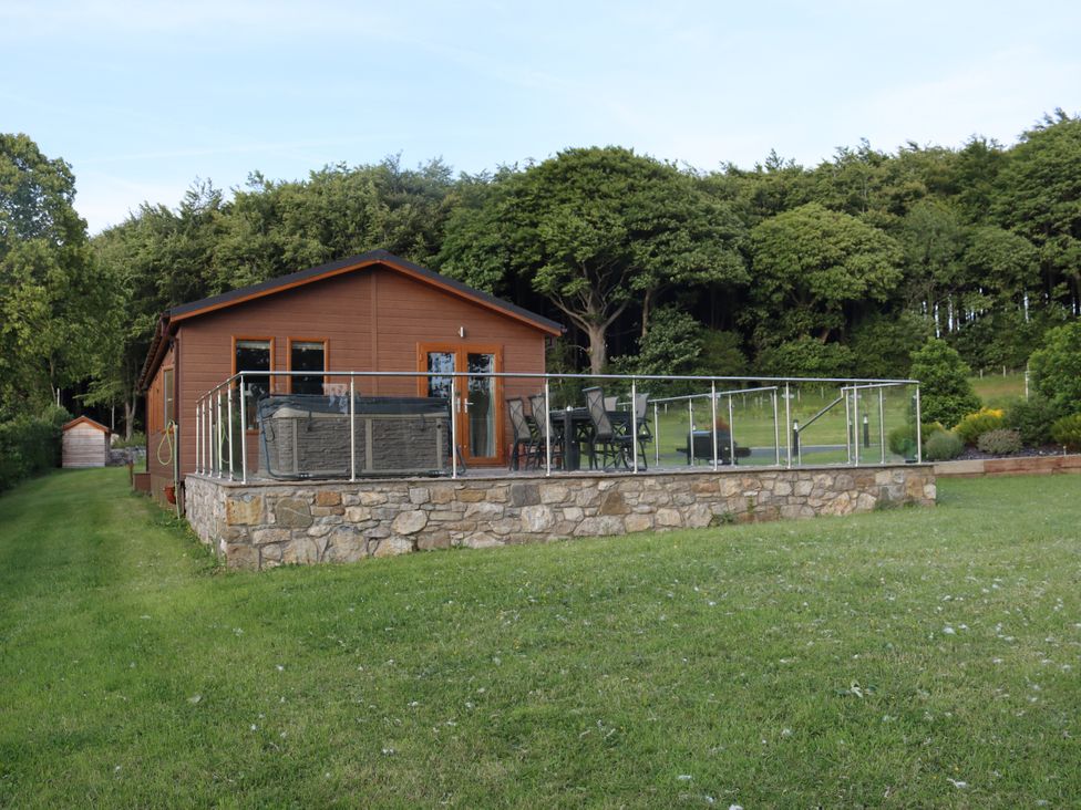 A cabin with a deck and garden at Pine Lodge in Lloc near Caerwys