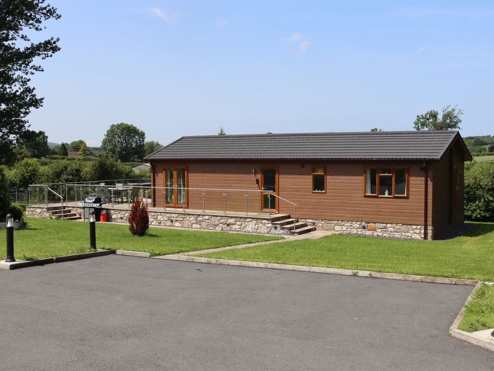 A house with a deck and grass area at Pine Lodge in Lloc near Caerwys