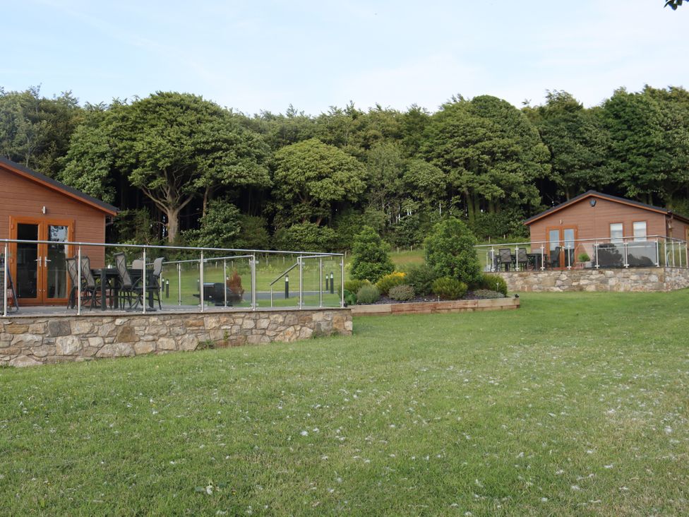 An outdoor area with lodges and seating at Pine Lodge in Lloc near Caerwys
