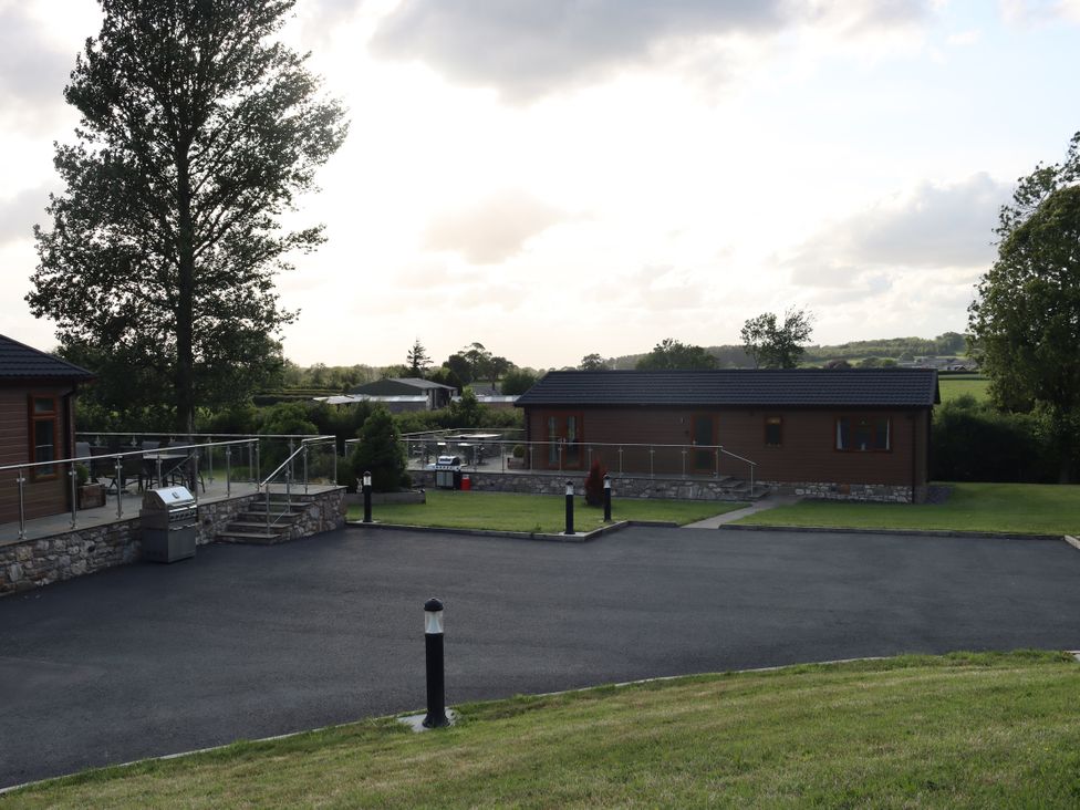 A view of log cabins and a paved driveway at Pine Lodge in Lloc near Caerwys
