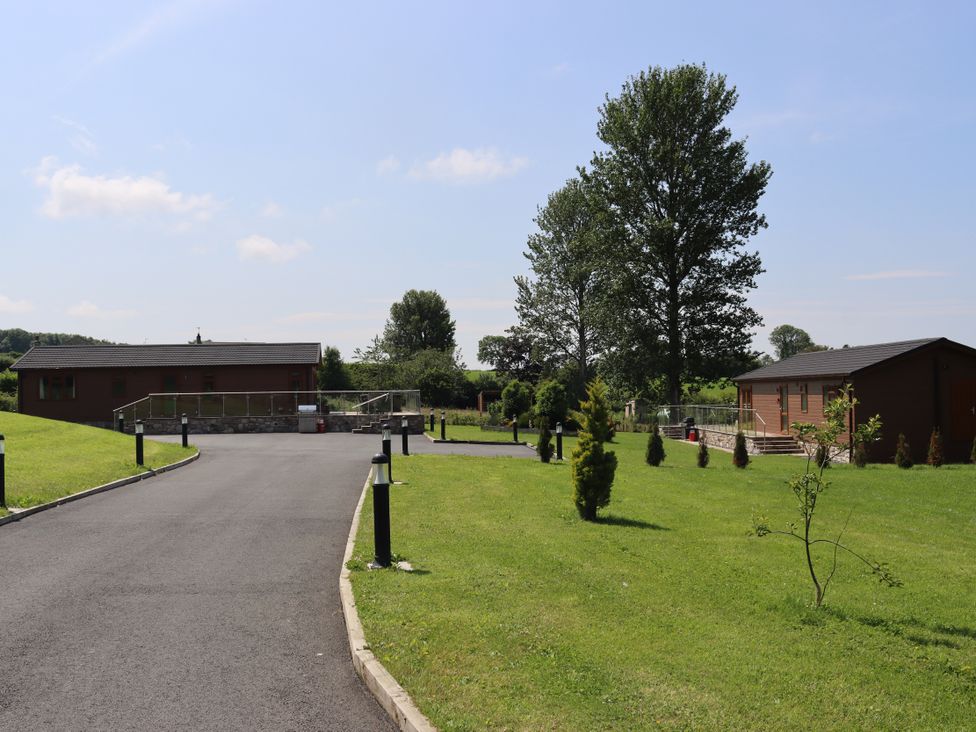 An outdoor area with lodges and grassy landscape at Pine Lodge in Lloc near Caerwys