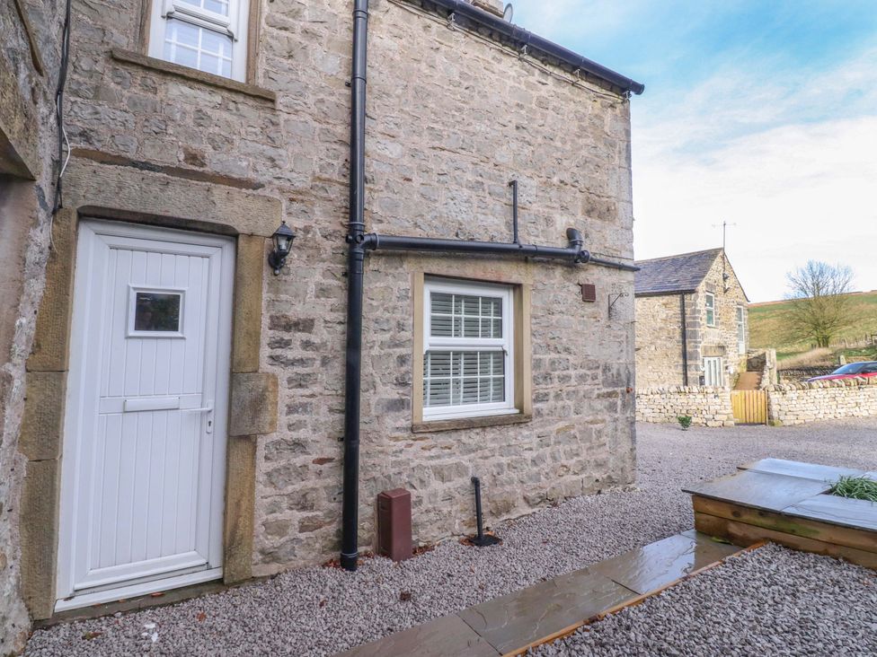 An outdoor area with a stone wall and a door at Cowside Farm Langcliffe near Settle