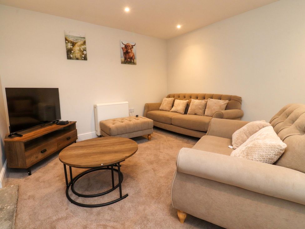 A living room with a sofa, coffee table and television at Cowside Farm Langcliffe near Settle