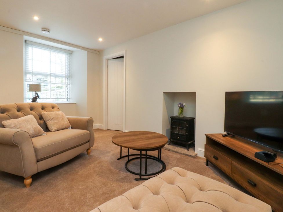 A living room with a sofa, coffee table, television and fireplace at Cowside Farm in Langcliffe near Settle