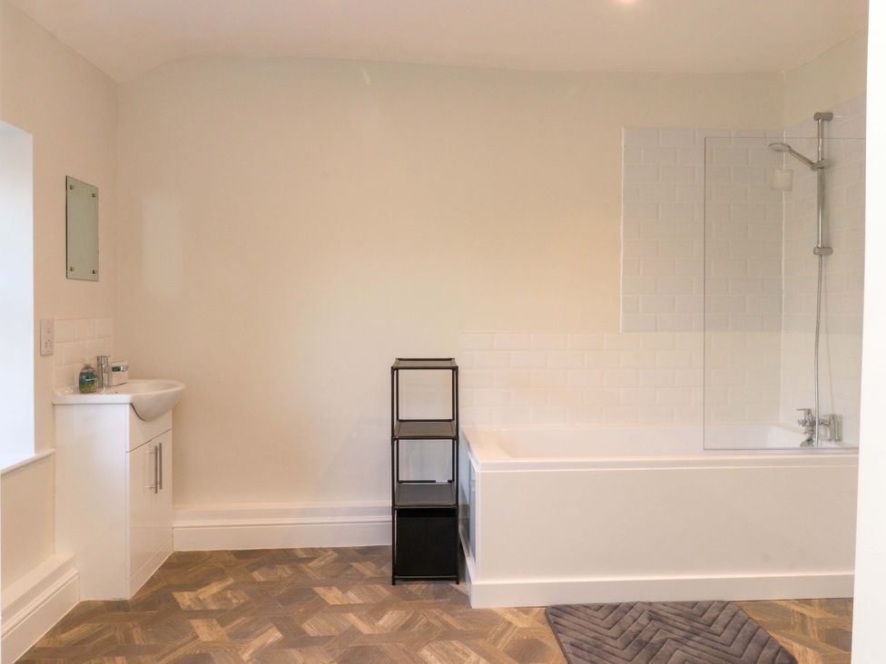 A bathroom with bathtub, sink, and storage unit at Cowside Farm in Langcliffe near Settle