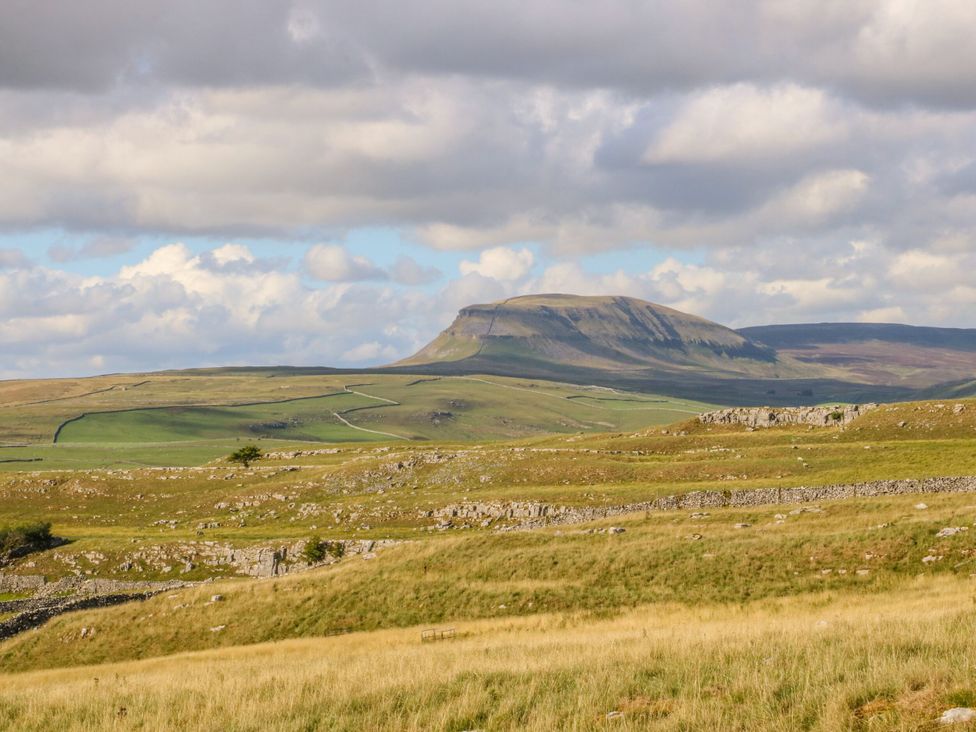 A landscape with a mountain and fields at Cowside Farm in Settle