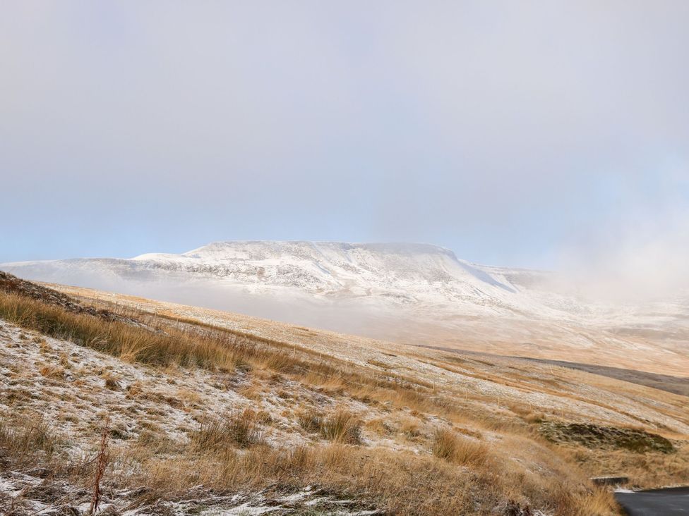 A mountain with snow and grass in the foreground at Cowside Farm in Settle