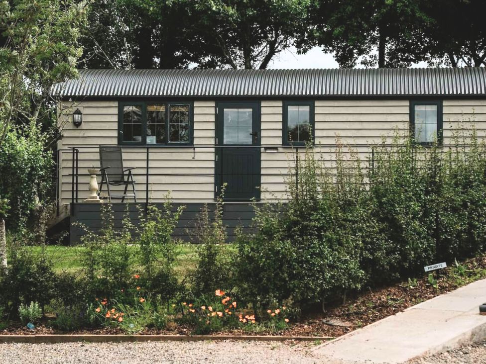 A cabin with a chair on the porch at The Lodge in Upton Warren