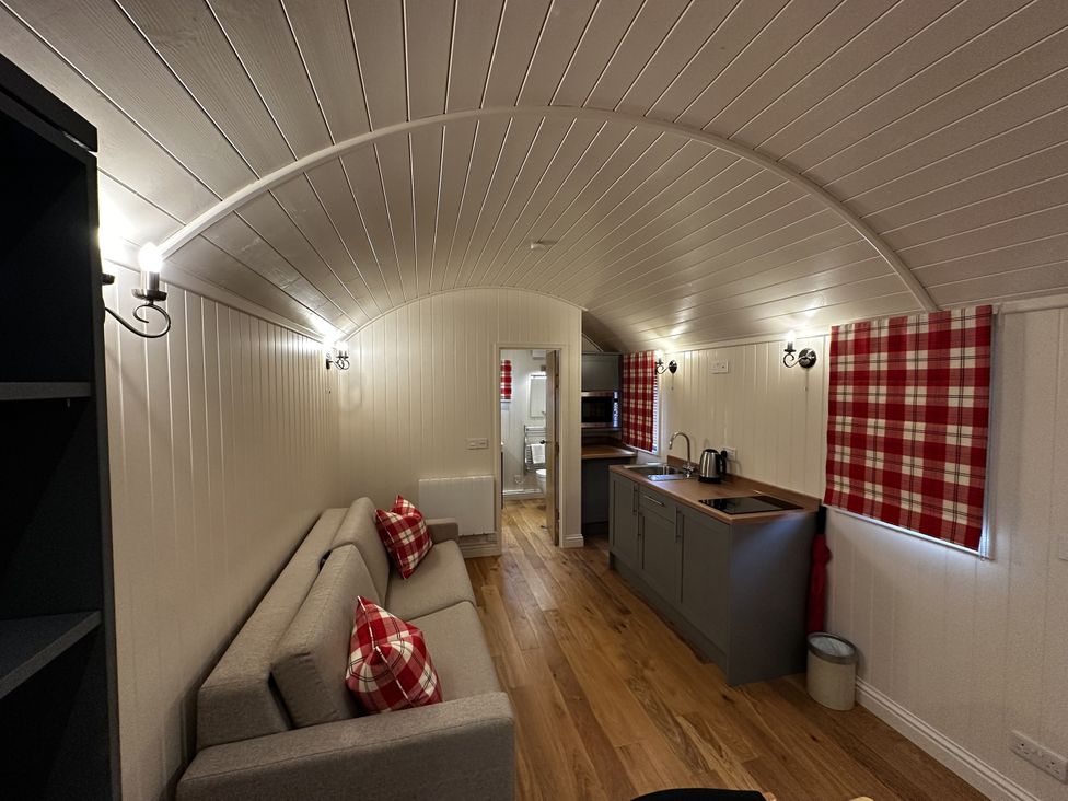 A living room with a sofa and kitchenette at The Lodge in Upton Warren