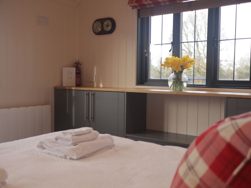 A bedroom with a bed and flowers on a shelf at The Lodge Upton Warren