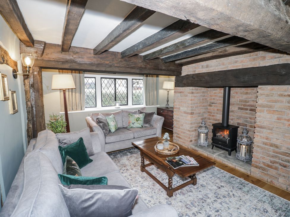 A living room with a fireplace and a sofa at Weston Cottage in Stratford-upon-Avon
