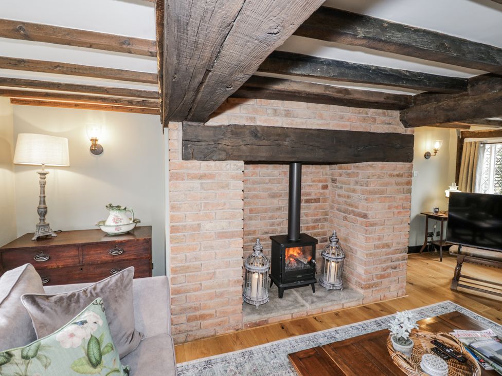 A living room with a fireplace and seating area at Weston Cottage in Stratford-upon-Avon
