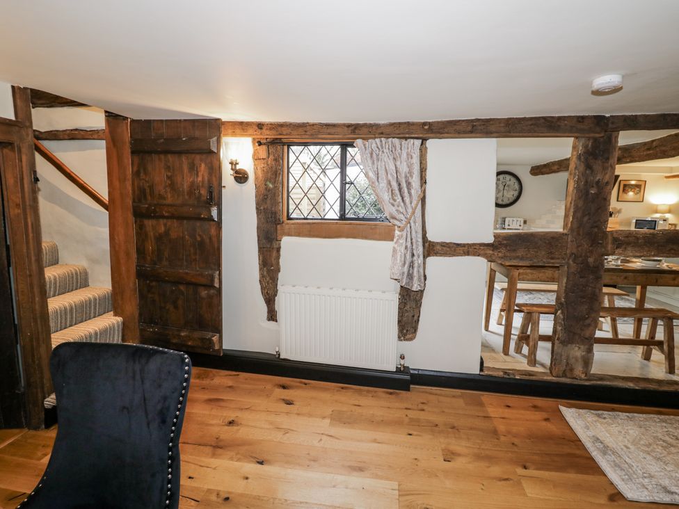 A hallway with a staircase and wooden door at Weston Cottage in Stratford-upon-Avon