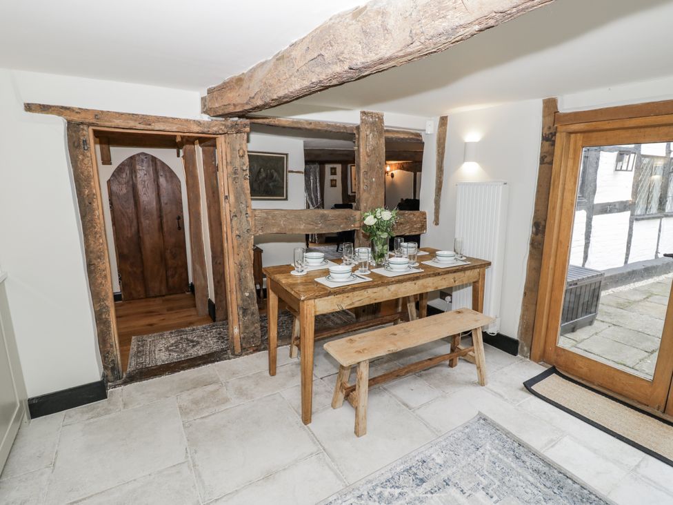 A dining room with a wooden table and bench at Weston Cottage Stratford-upon-Avon
