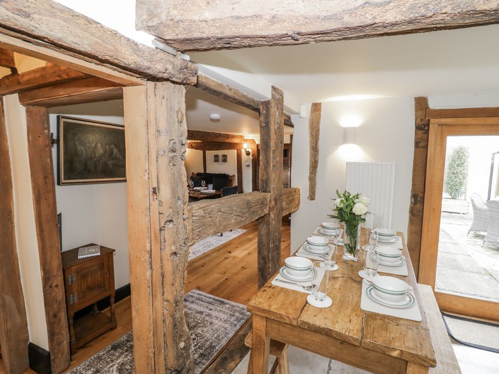 A dining room with a wooden table set for a meal at Weston Cottage in Stratford-upon-Avon
