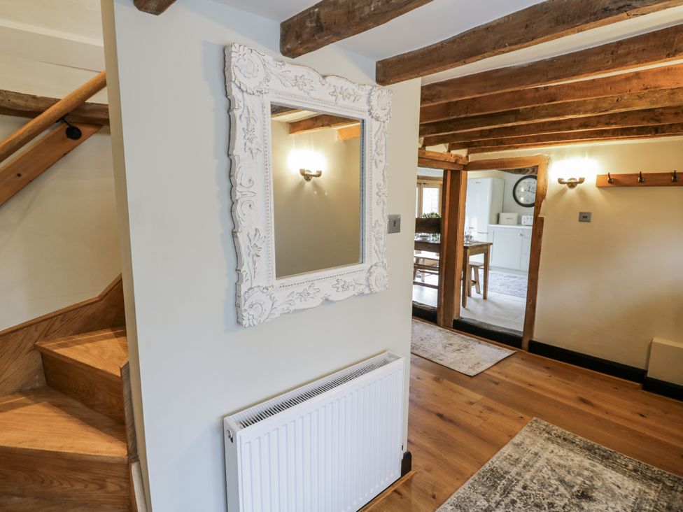 A hallway with a mirror and staircase at Weston Cottage in Stratford-upon-Avon