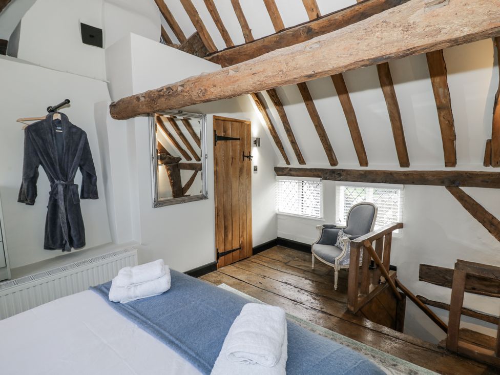 A bedroom with a chair and a mirror at Weston Cottage Stratford-upon-Avon