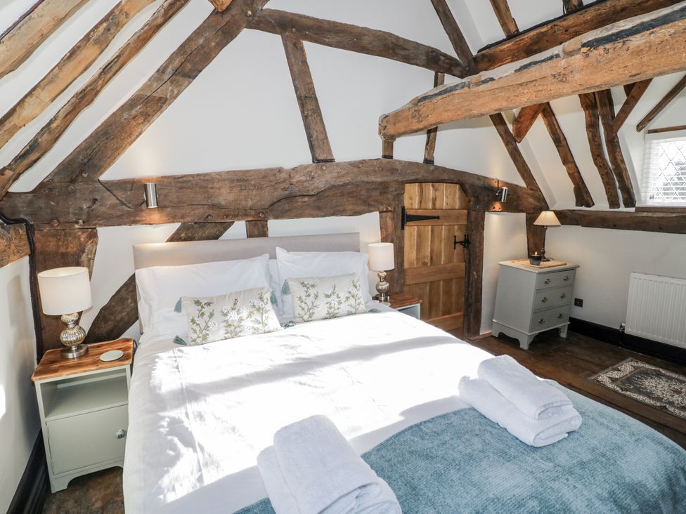 A bedroom with wooden beams and a bed at Weston Cottage in Stratford-upon-Avon