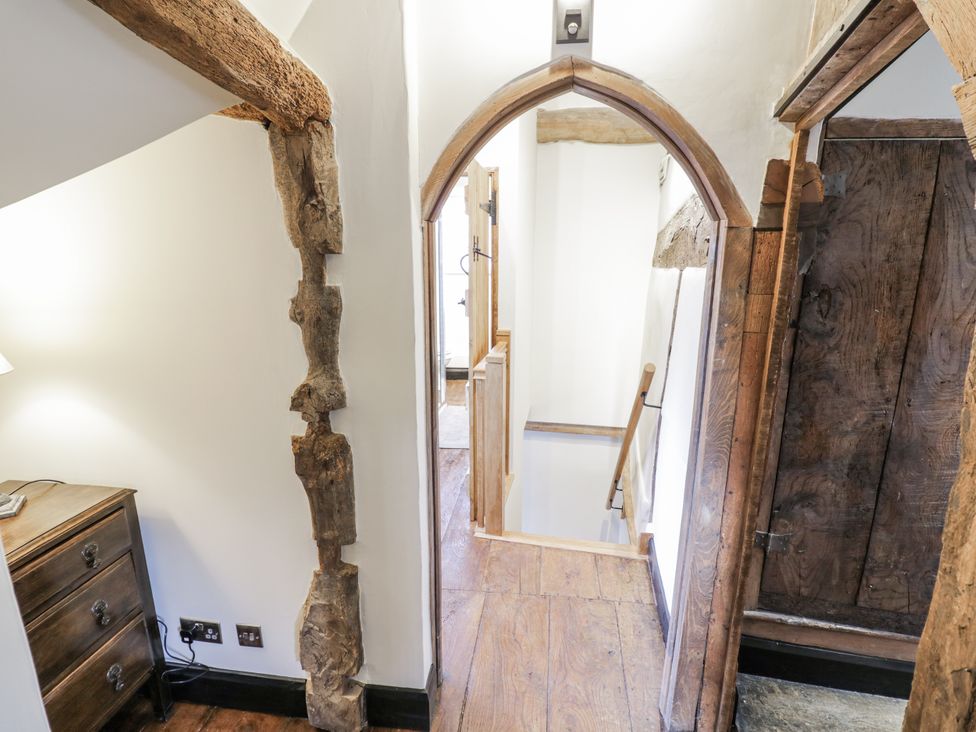 A hallway with a staircase and wooden door at Weston Cottage Stratford-upon-Avon