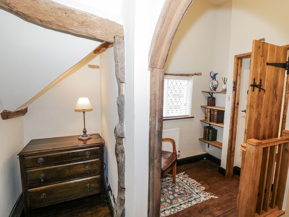 A landing with a chest of drawers and a wooden chair at Weston Cottage in Stratford-upon-Avon