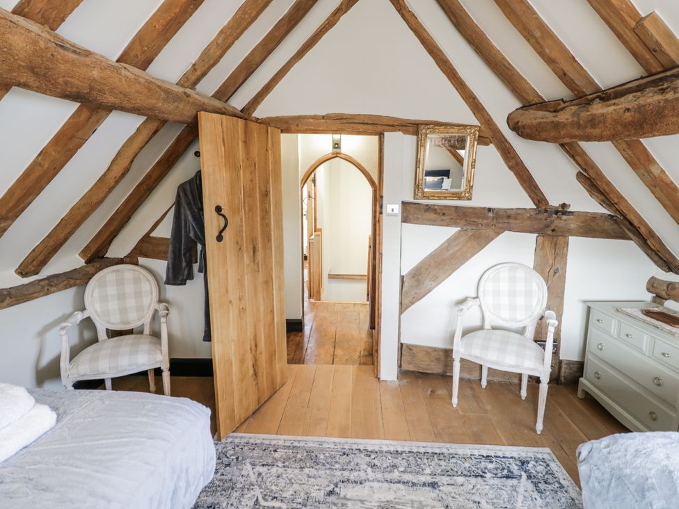 A bedroom with wooden beams and an opening to another room at Weston Cottage in Stratford-upon-Avon