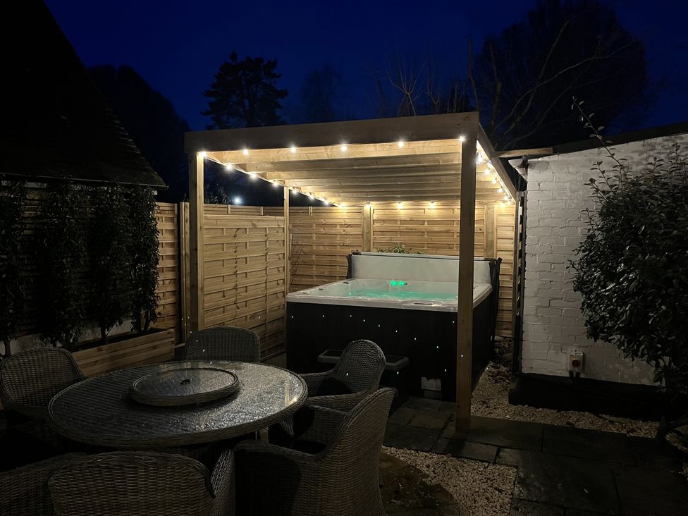 A garden with a hot tub and a patio table at Weston Cottage in Stratford-upon-Avon