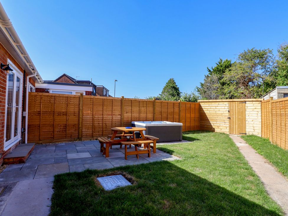 A garden with a patio table and hot tub at 1 Ashcott Place Burnham-On-Sea